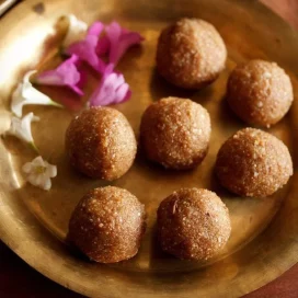 Red rice laddu displayed on a copper plate